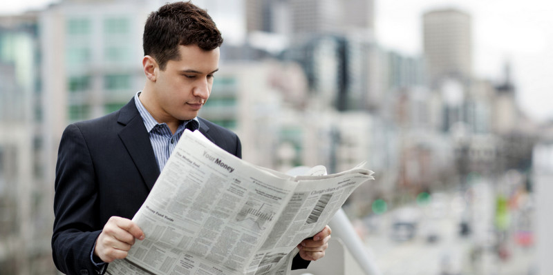 Mixed race businessman reading newspaper