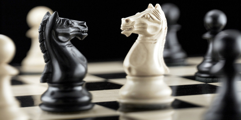Knight chess pieces facing each other on chess board